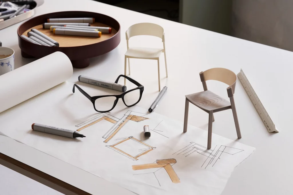 A designer's workspace showcasing drawing tools & sketches of chairs.