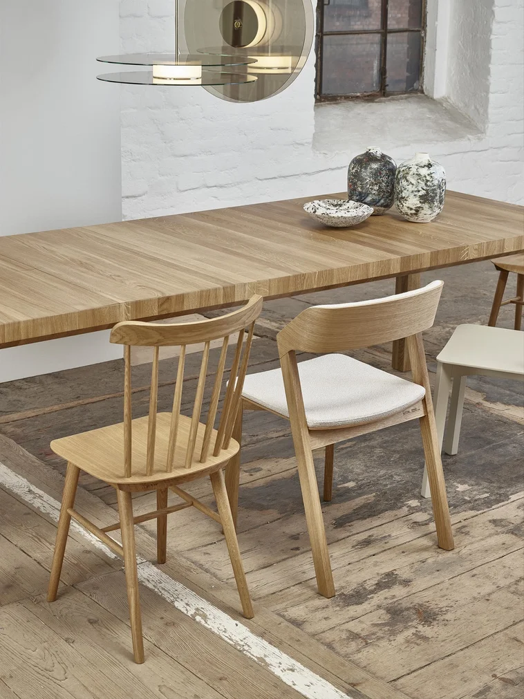 A wooden dining table with 2 designer furniture chairs.