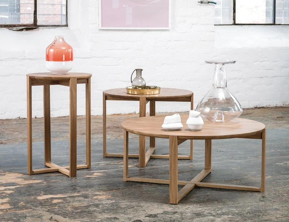 A trio of wooden coffee tables in a loft-style room. 