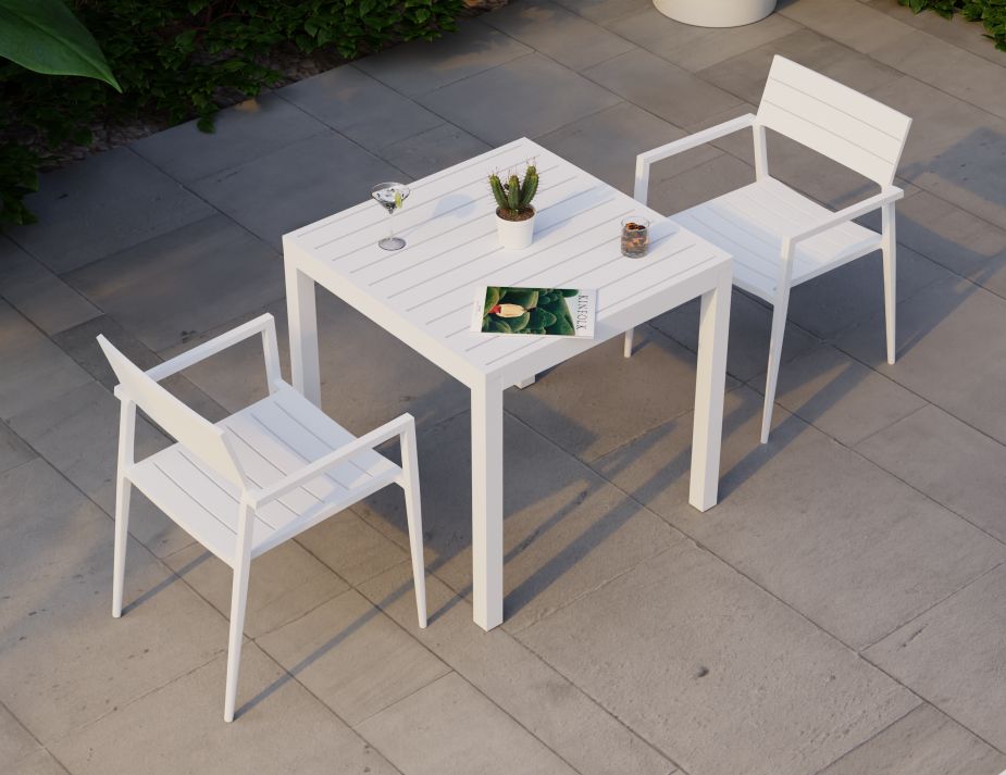 A pristine white outdoor furniture set is showcased against a muted backdrop of concrete tiles and verdant greenery. The square table is adorned with a refreshing drink, a potted cactus, and a magazine, suggesting a relaxed afternoon. The sleek chairs, with their simple lines and modern design, complement the table perfectly. 