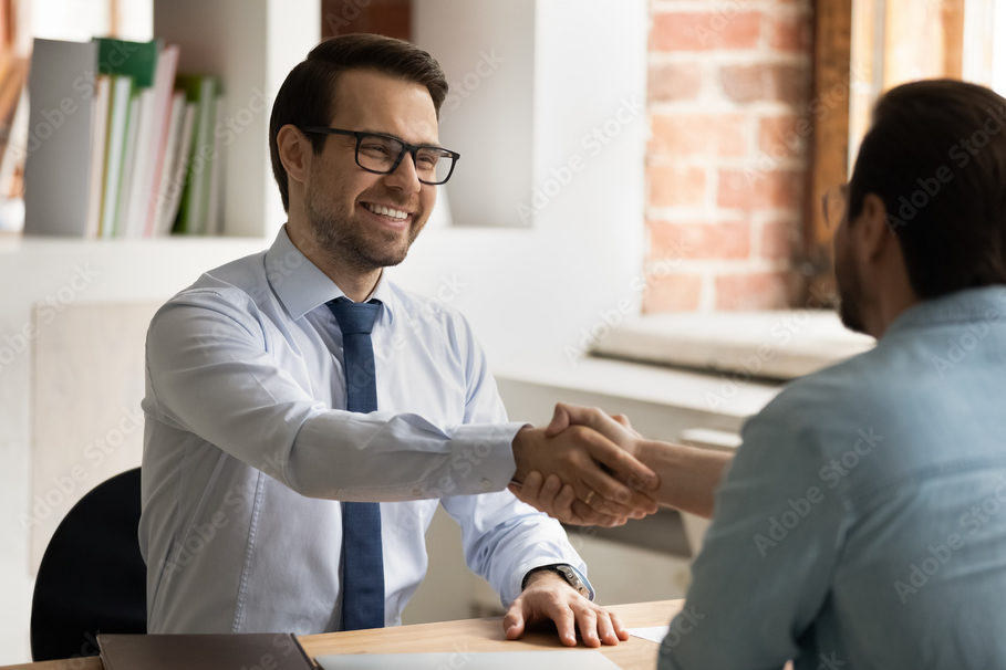 An interior designer and client shaking hands across a table.