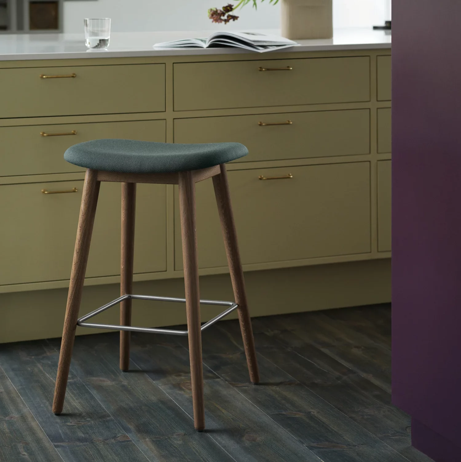 A teal cushioned kitchen stool with wooden leg.
