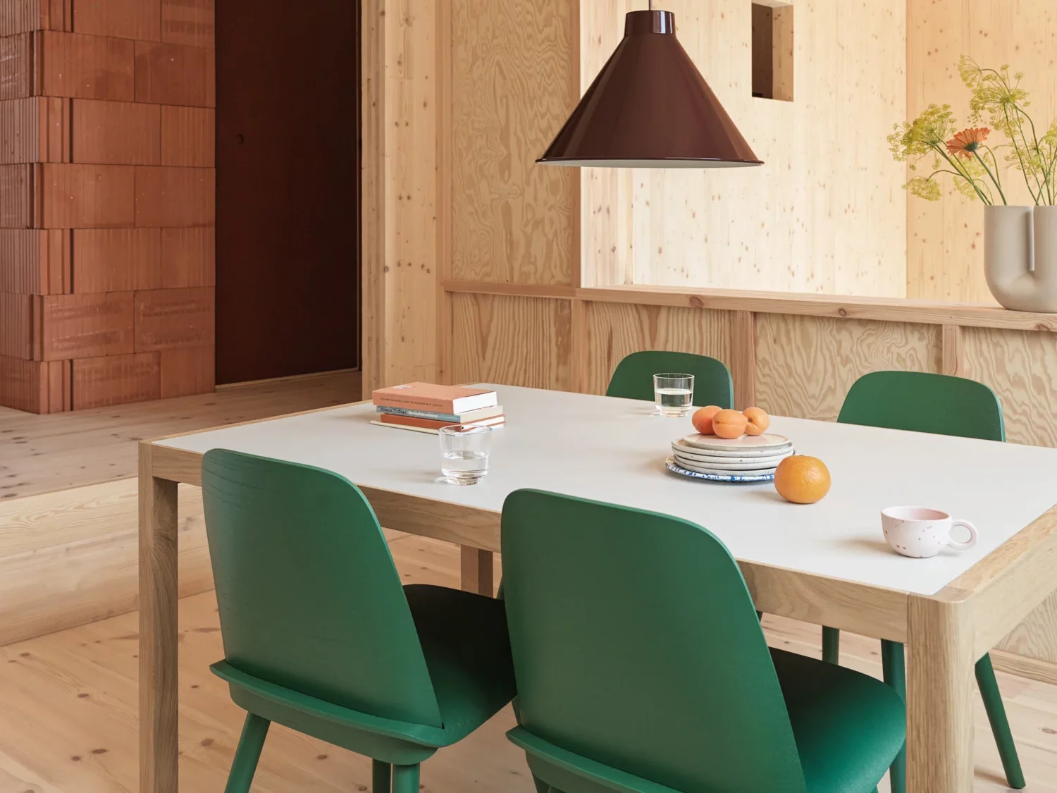 A dining room with white table surrounded by green chairs. 