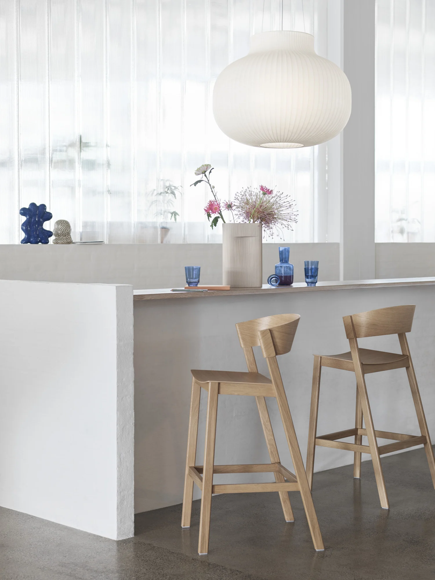 Bright kitchen bar with wooden stools and pendant light.