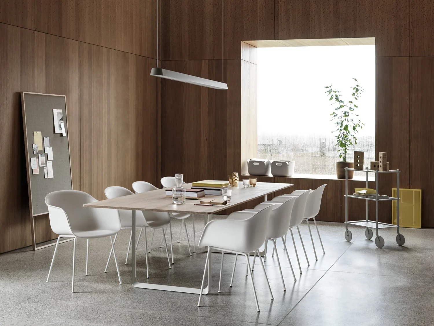 Conference room with long wooden table surrounded by white chairs.