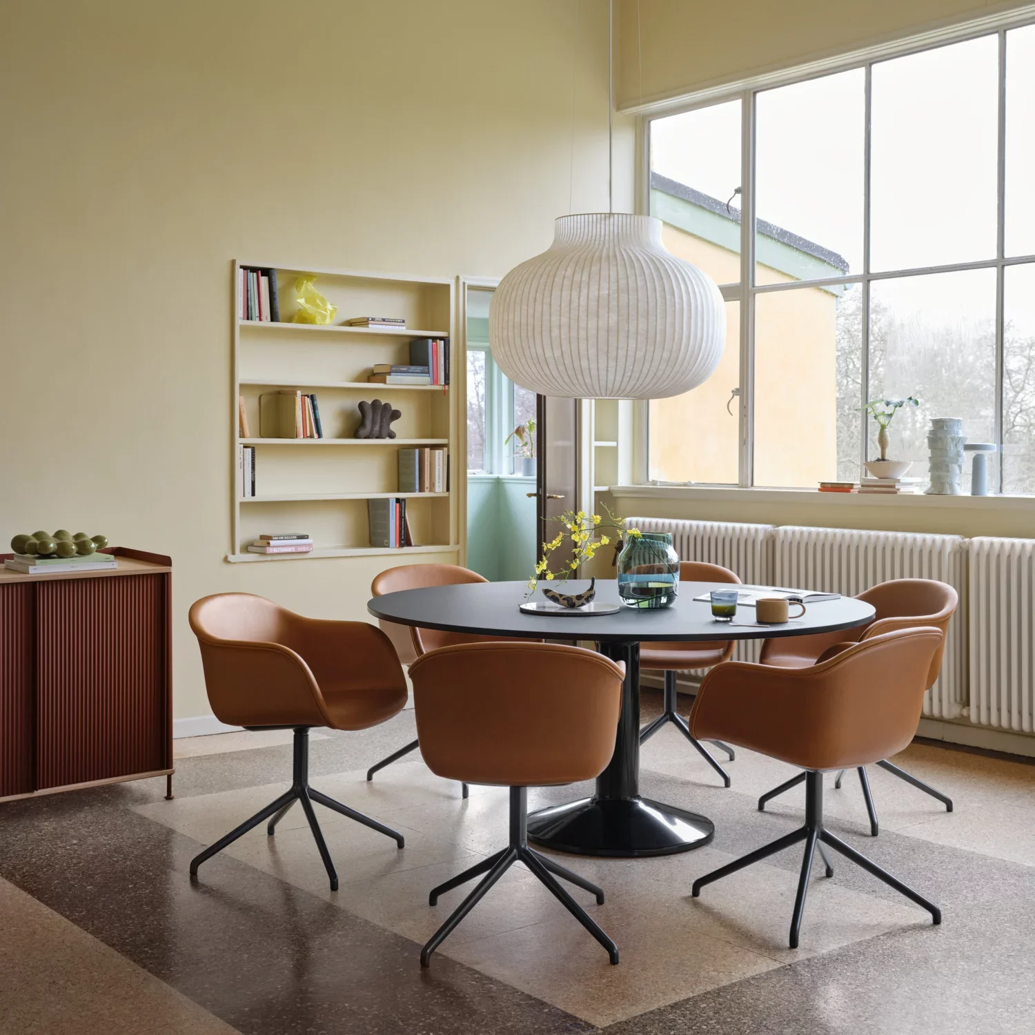 Dining area with brown upholstered chairs around a black table.