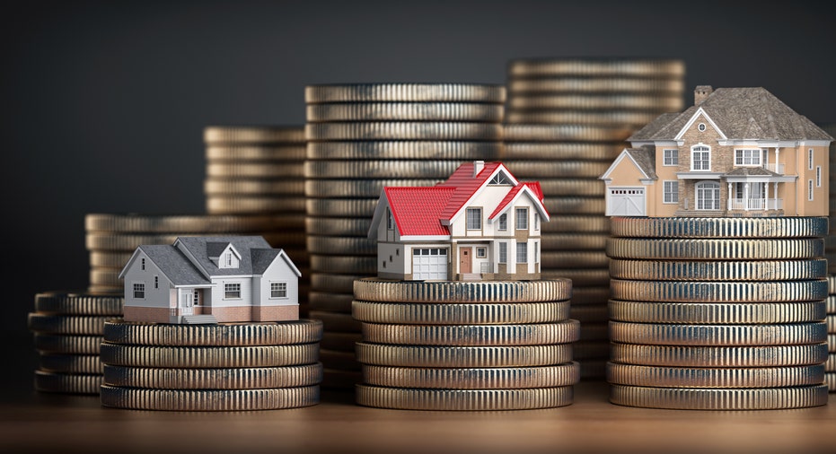 Miniature house models placed atop stacks of coins.