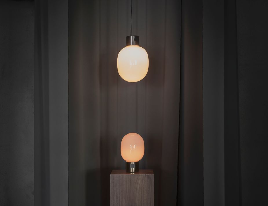 Modern pendant & table lamp with warm glow against drapes.

