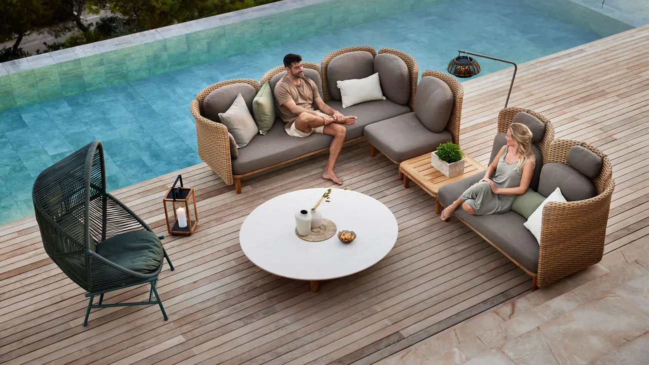 A poolside setting with woven sofas and chairs.