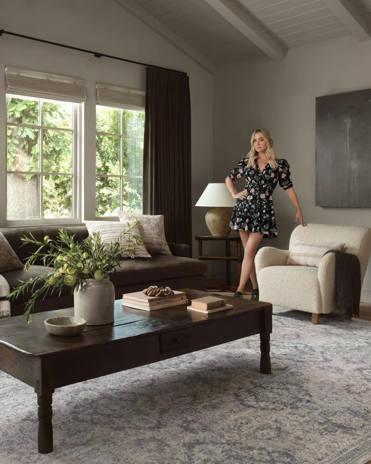 Woman standing in cozy, elegant living room interior.