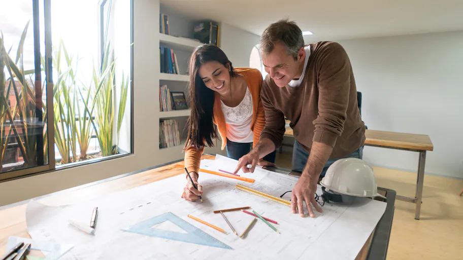 A man and woman, discussing architectural plans.