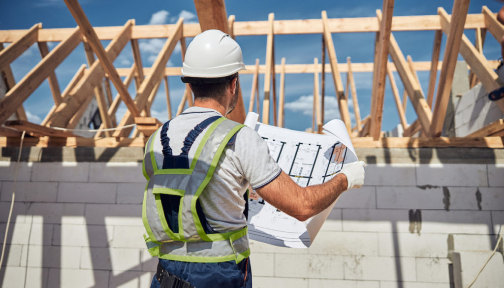 An architect examining architectural plans on a construction site.