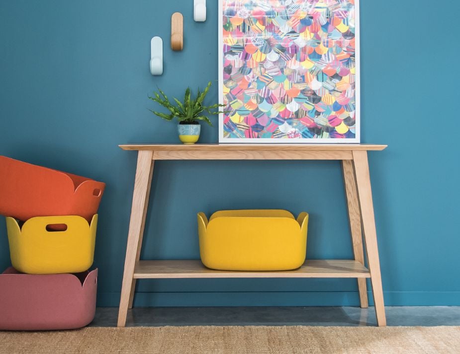 Wooden console table against a teal wall. 