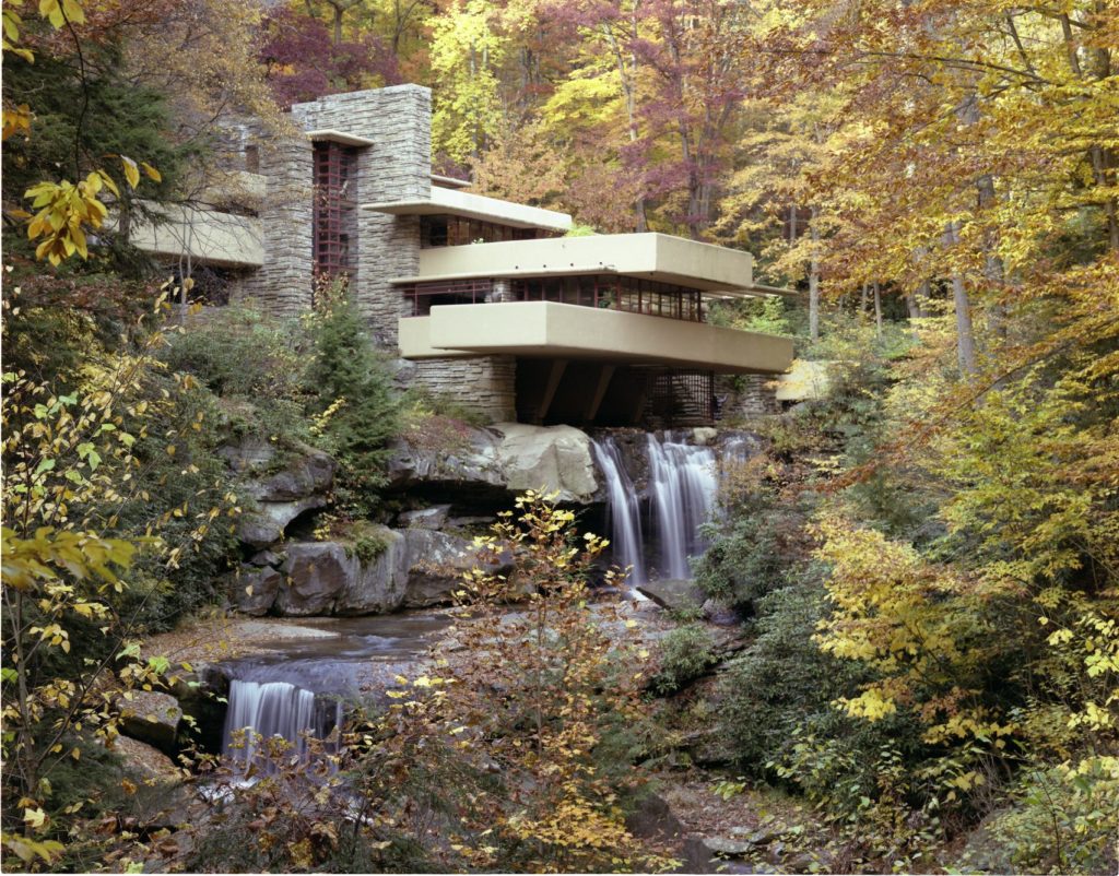 A modern architectural house, built with stone over a cascading waterfall.