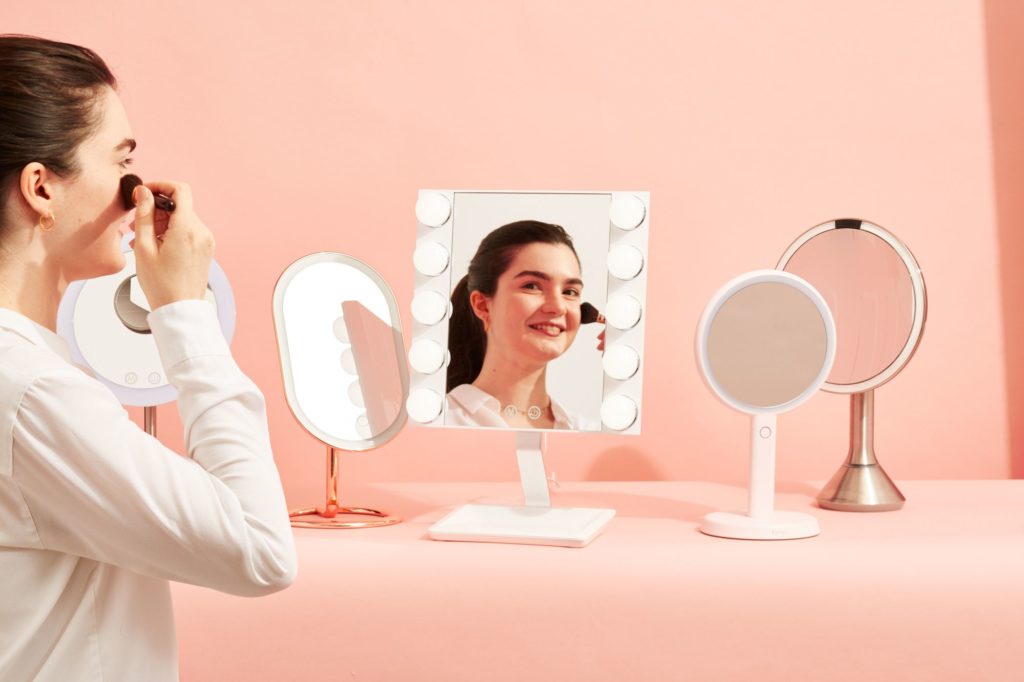 A woman in applying makeup in front of a mirror.