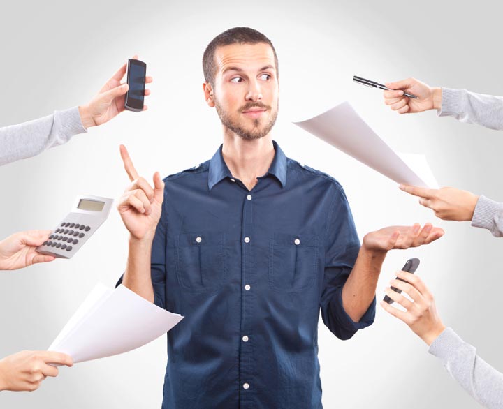 istock small Overwhelmed man in a blue shirt, surrounded by hands.