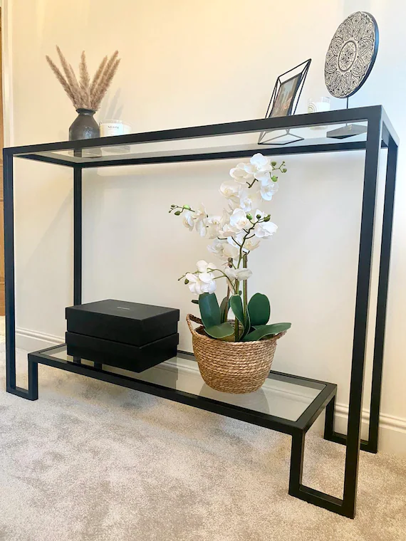 Black metal console table set against a cream wall. 