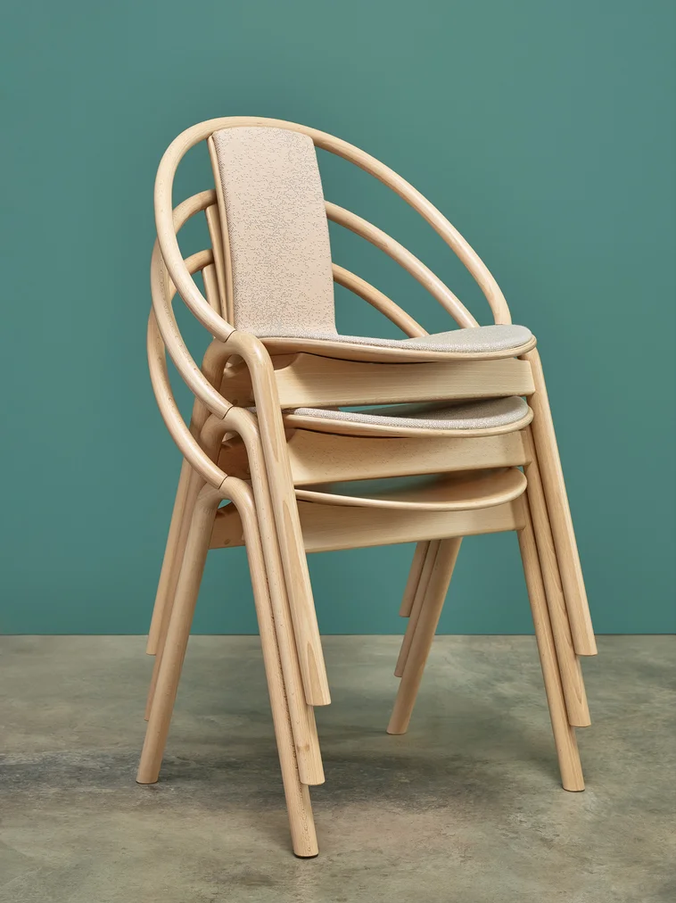 Bentwood chairs stacked together in a green background.