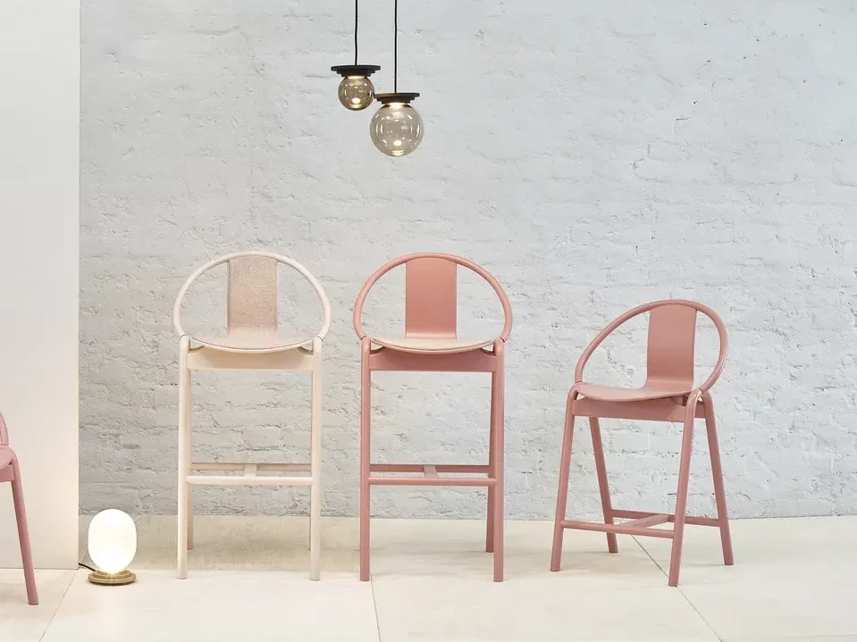 Pastel pink metal chairs set against a white-bricked wall.