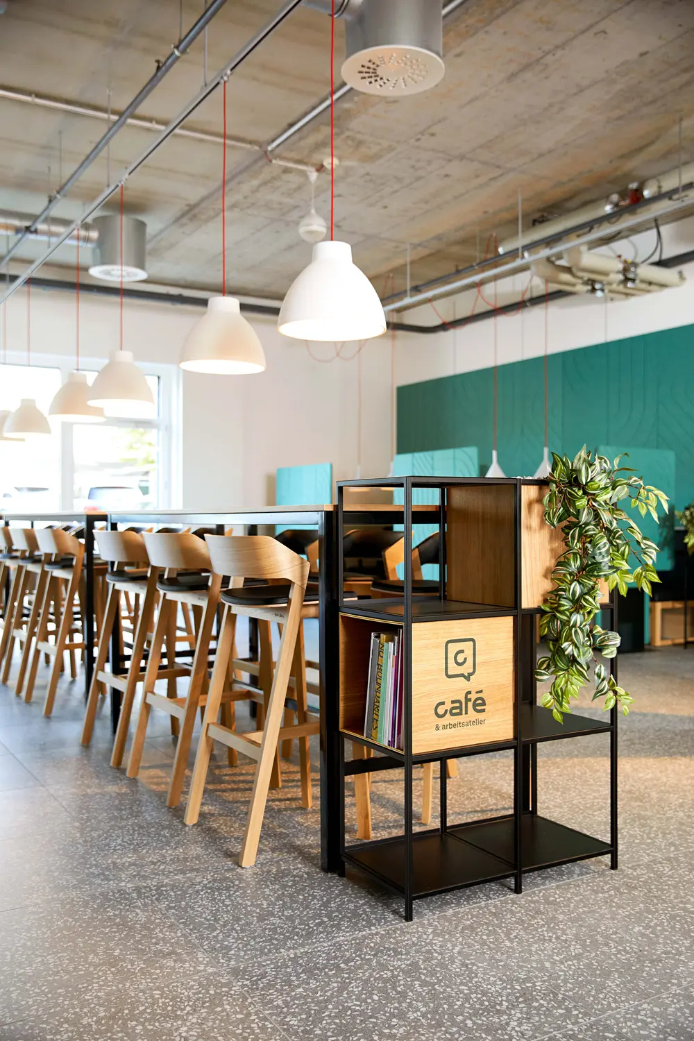 Modern cafe interior with hanging lights and wooden chairs.