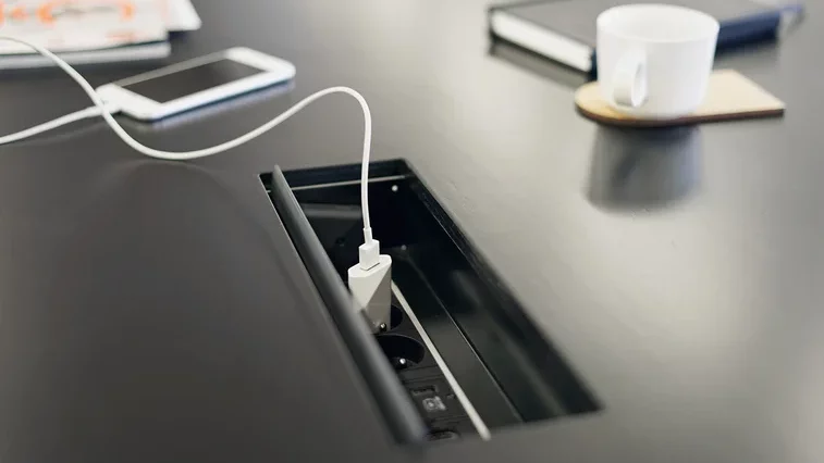 A close-up view of a black table surface with a power socket.