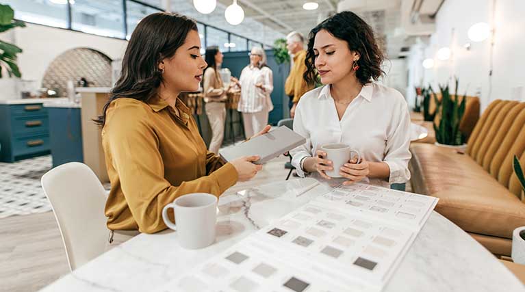 Two women sitting and discussing at a table in an office space.