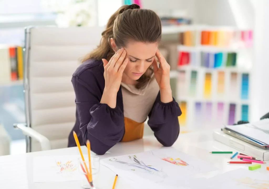 Stressed female interior designer at her desk with sketches.