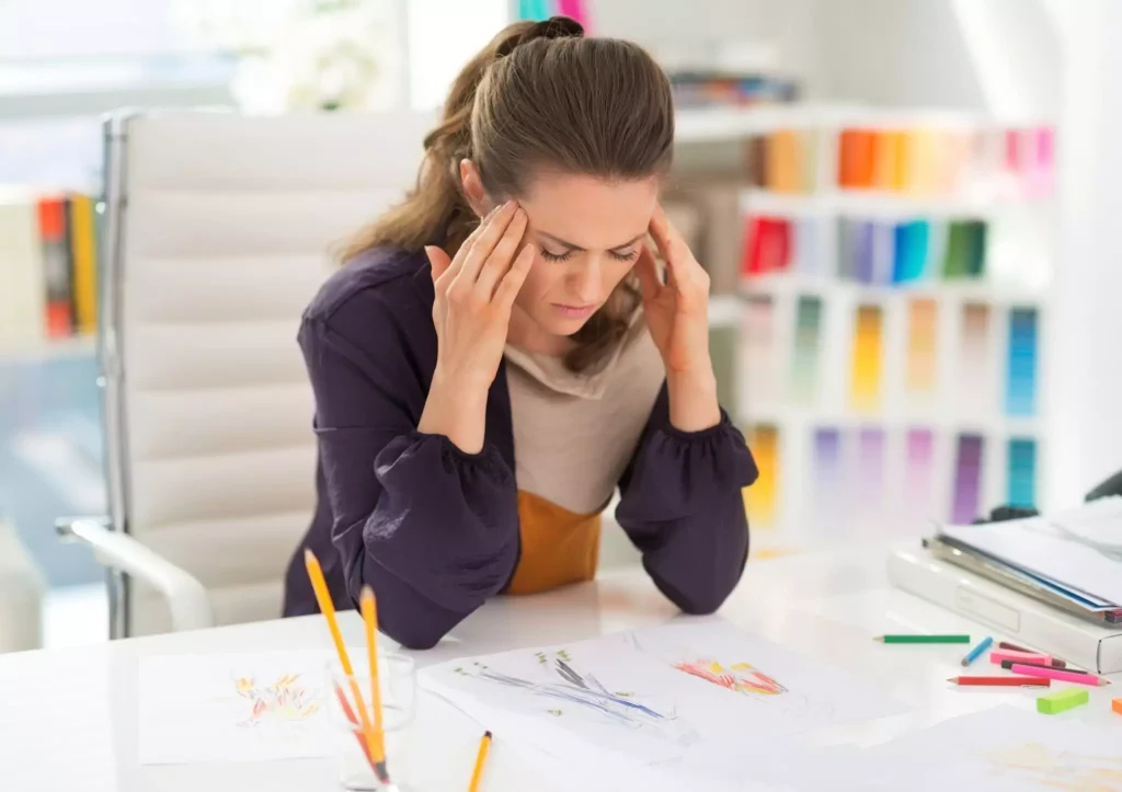 interior designer problems scaled Stressed female interior designer at her desk with sketches.