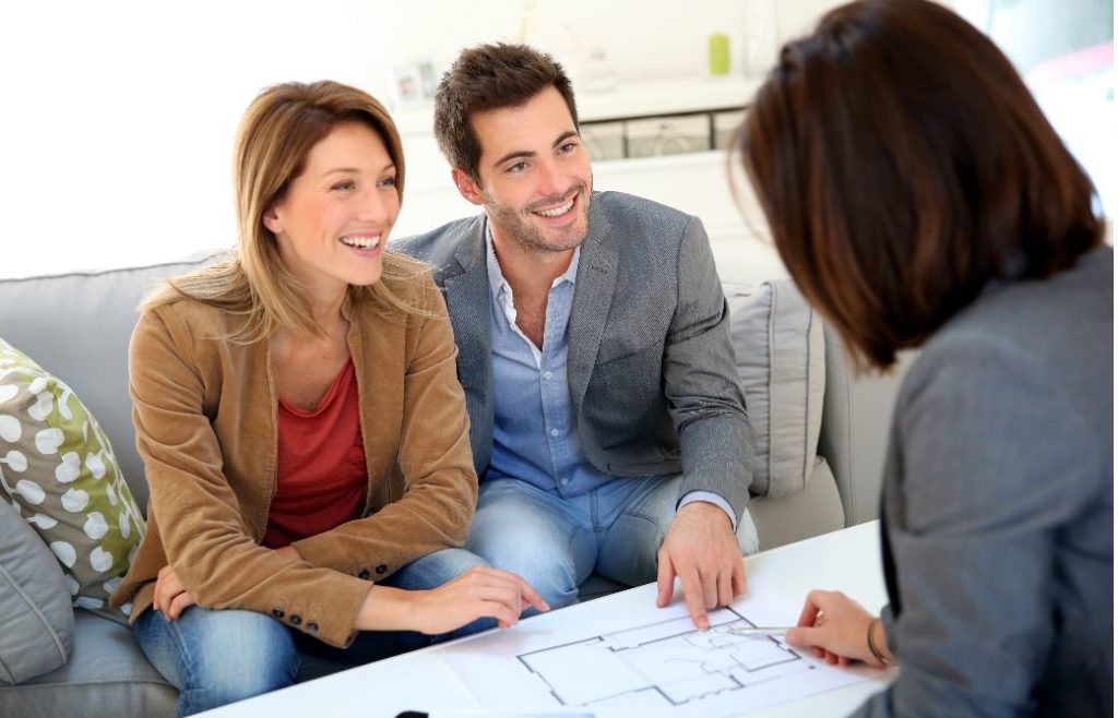 Joyful couple discussing house plans with a female architect.