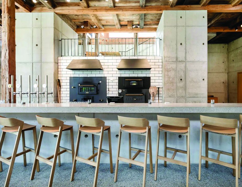 A rustic yet modern cafe interior with wooden barstools.