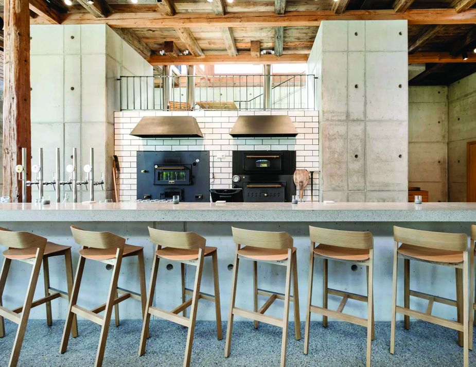 A rustic yet modern cafe interior with wooden barstools.