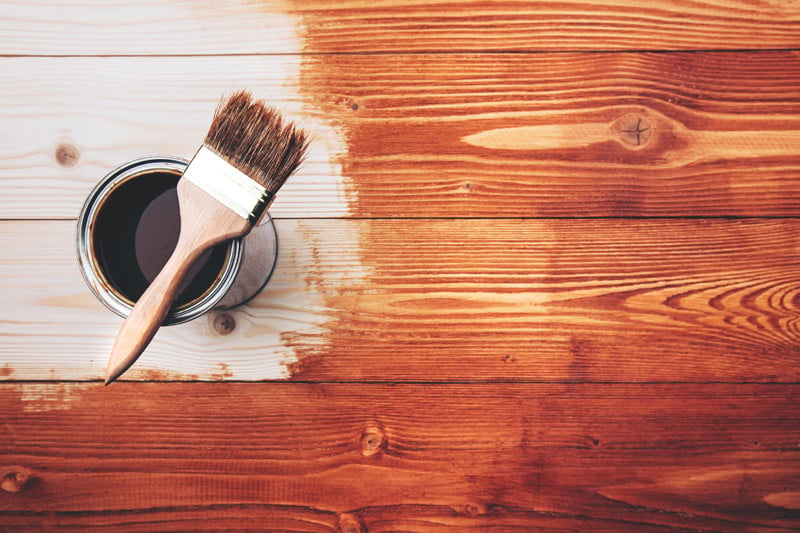 Open can of wood stain with a brush.